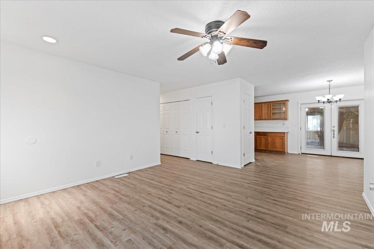 Unfurnished living room featuring light wood-style flooring, ceiling fan, and a chandelier