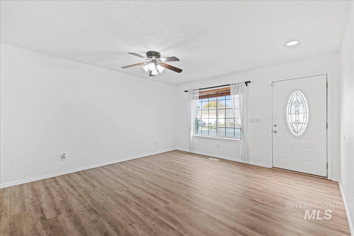Entrance foyer with light wood finished floors, a ceiling fan, and a textured ceiling