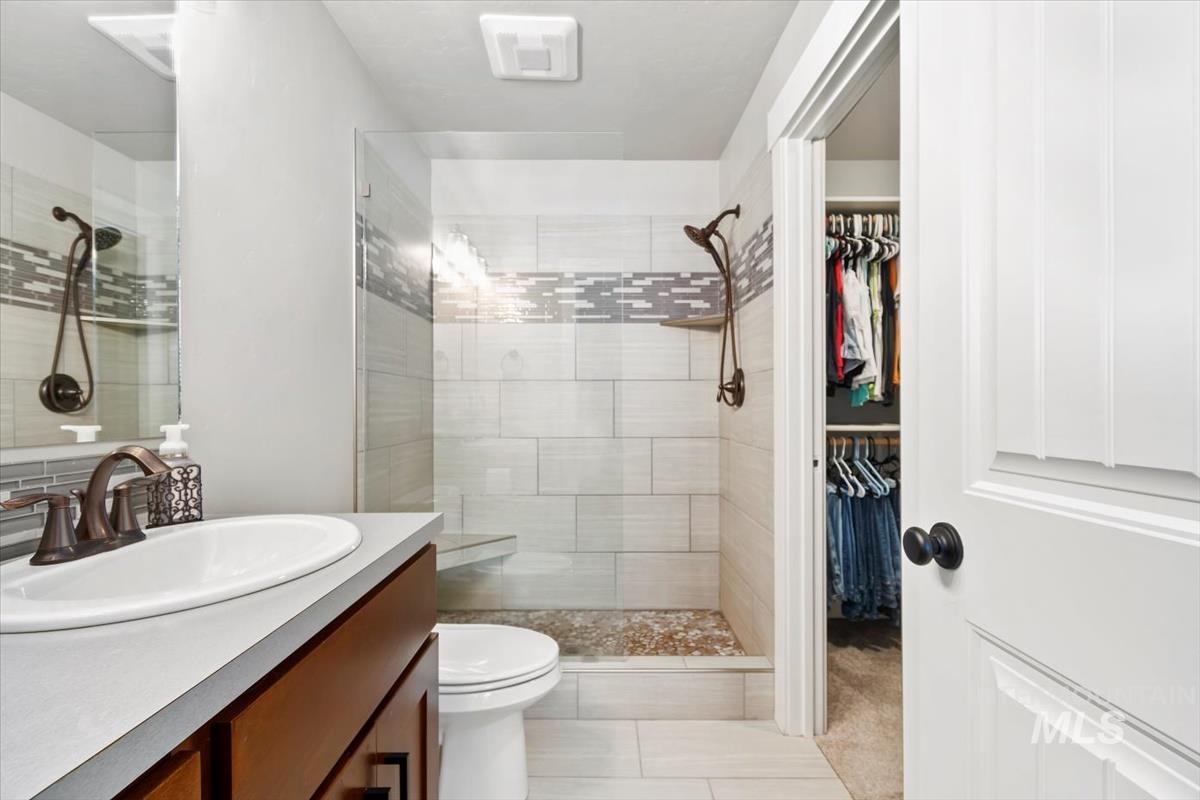Bathroom with vanity, a shower stall, a walk in closet, and light tile patterned floors