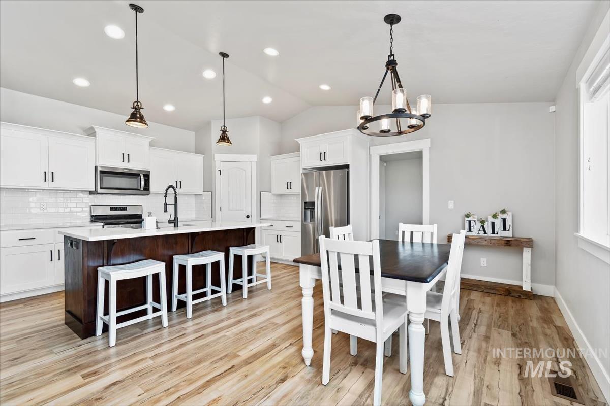 Dining room with vaulted ceiling, a chandelier, light wood-style floors, and recessed lighting