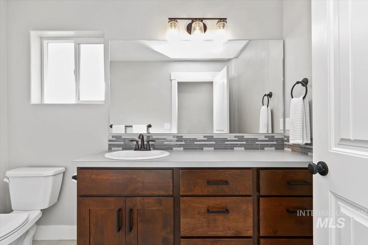 Half bath featuring vanity and tasteful backsplash