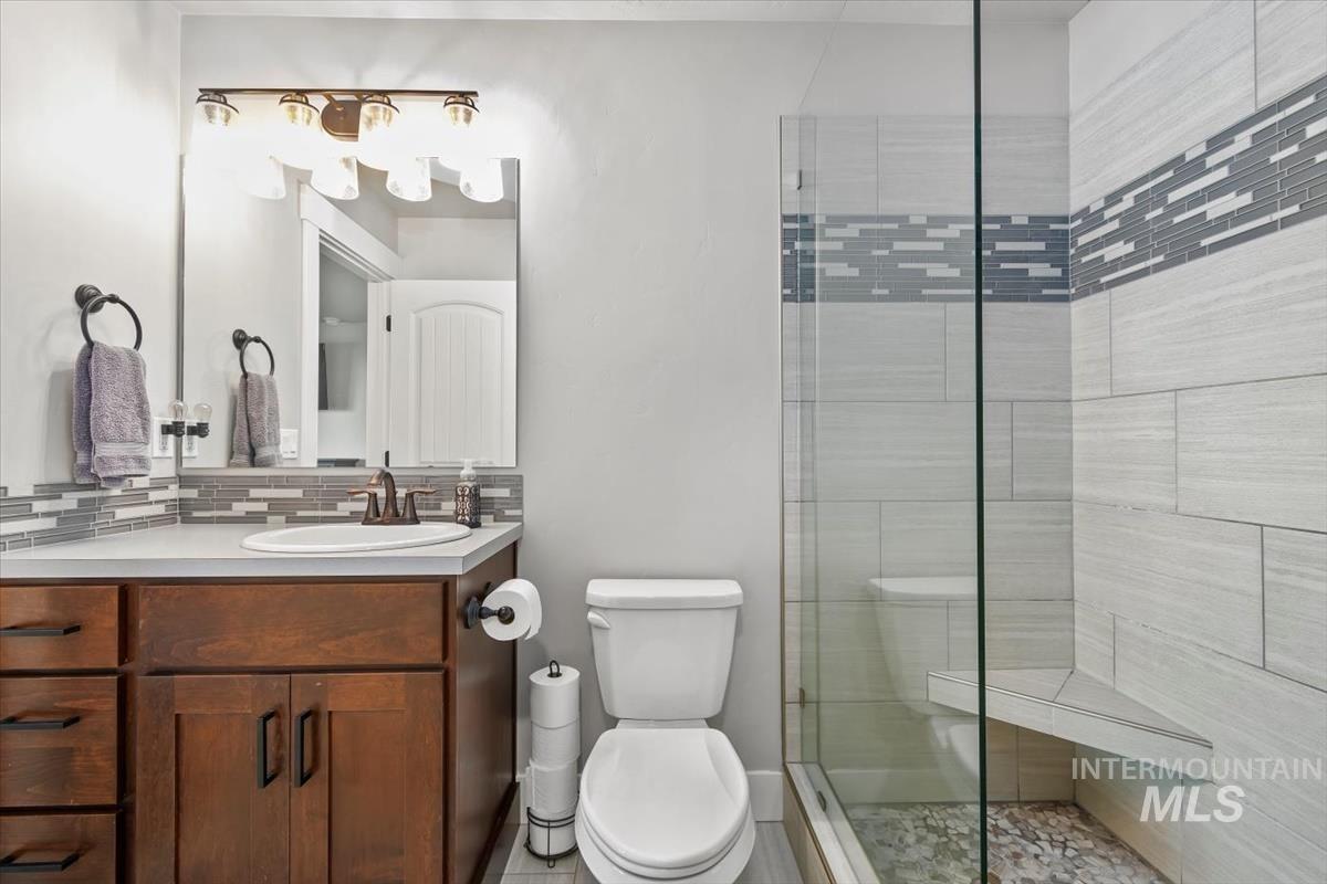 Full bath featuring vanity, a shower stall, and backsplash