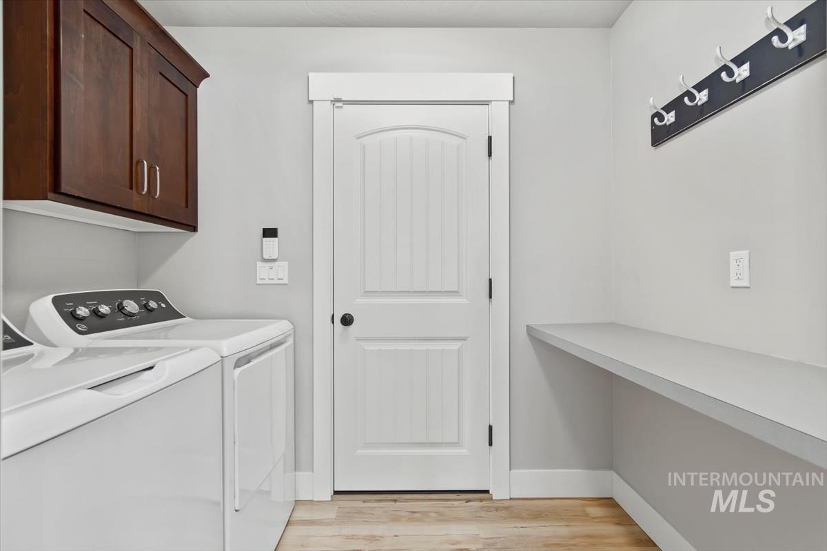 Laundry area with washer and dryer, light wood-type flooring, and cabinet space