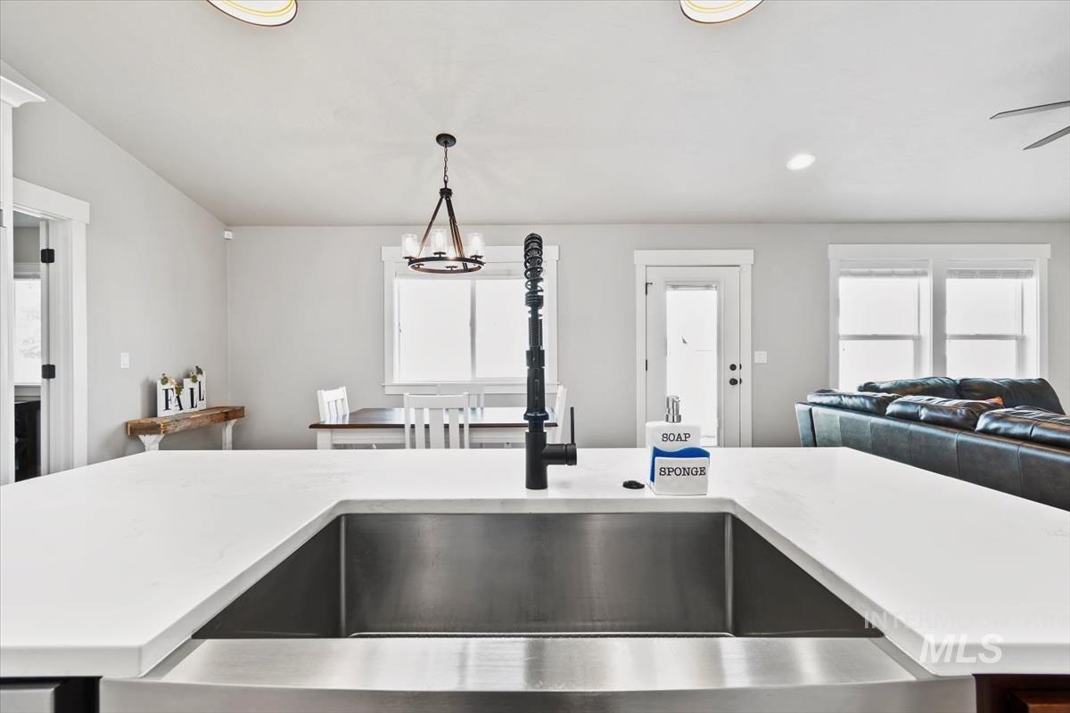 Kitchen with open floor plan, decorative light fixtures, light stone counters, and recessed lighting
