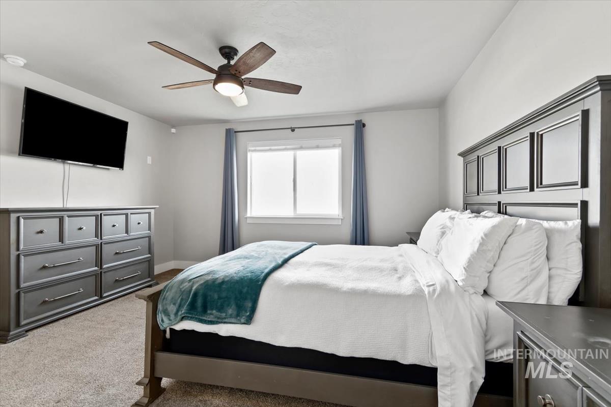 Carpeted bedroom with ceiling fan and baseboards