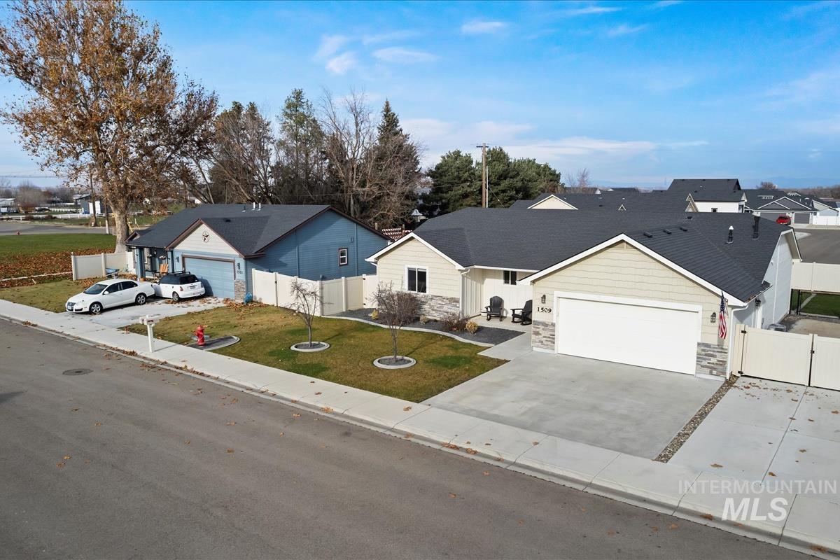 Ranch-style house featuring stone siding, concrete driveway, a gate, a garage, and a residential view