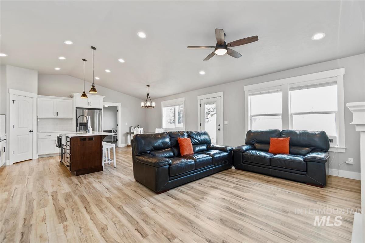 Living area with recessed lighting, light wood-type flooring, lofted ceiling, ceiling fan, and a chandelier