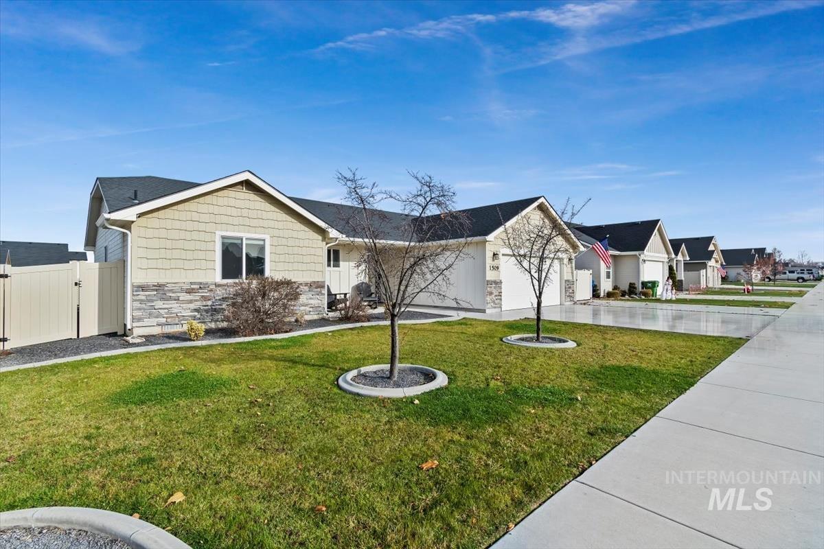 Single story home with stone siding, a front lawn, driveway, and an attached garage