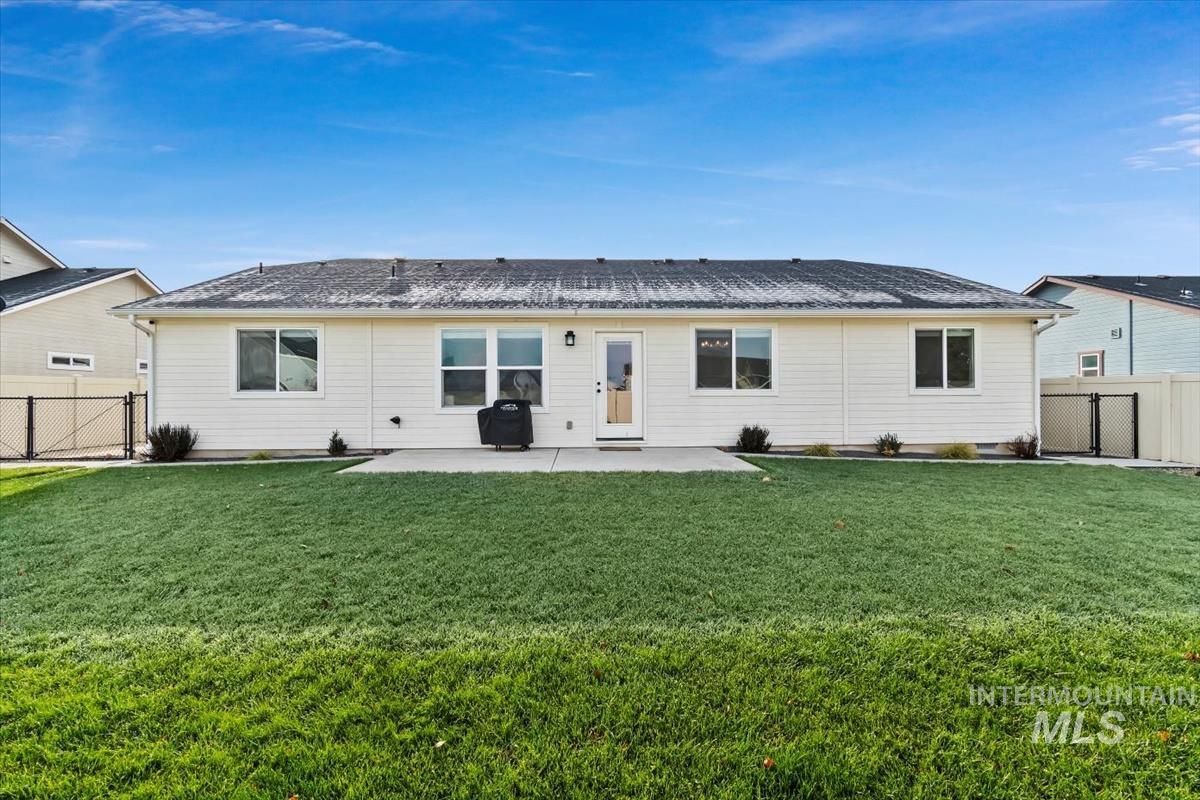 Back of house with a gate, a patio area, a fenced backyard, and a shingled roof