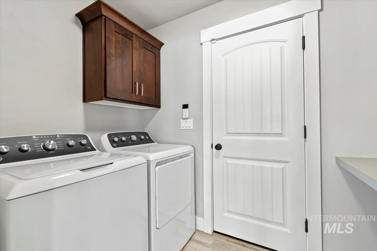 Laundry area featuring cabinet space, washing machine and dryer, and light wood finished floors