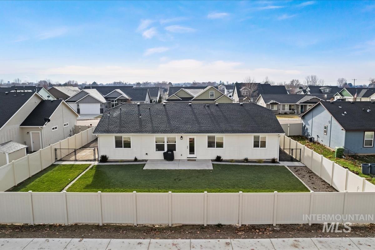View of front of home with a residential view, a patio, a fenced backyard, and roof with shingles