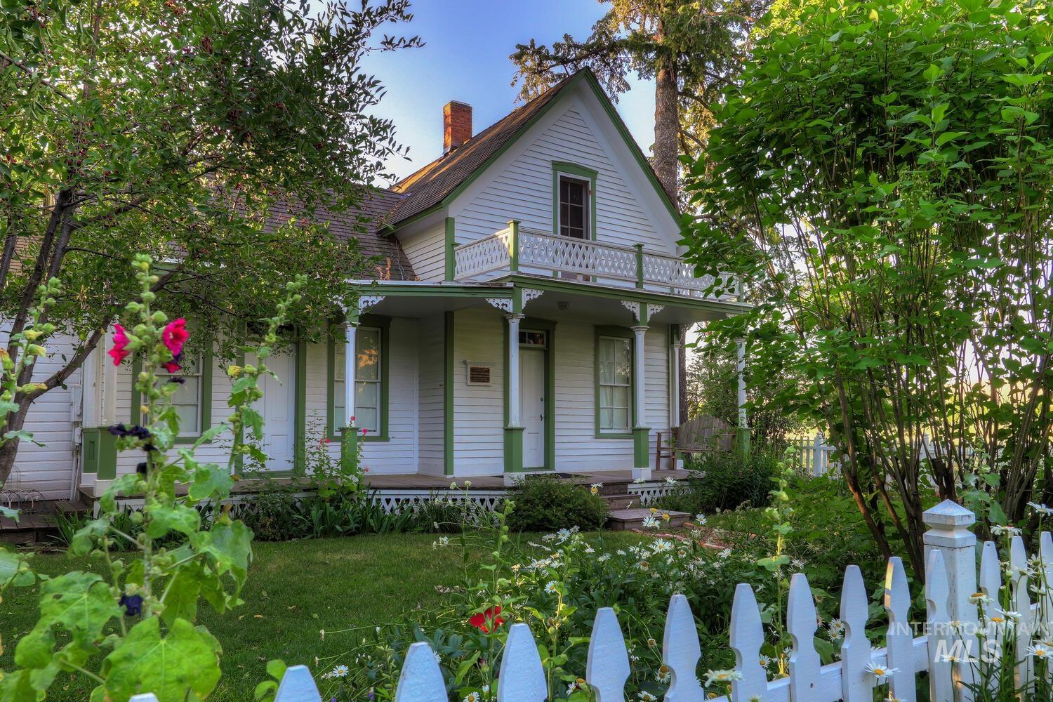 View of front of home with covered porch, a balcony, and a chimney