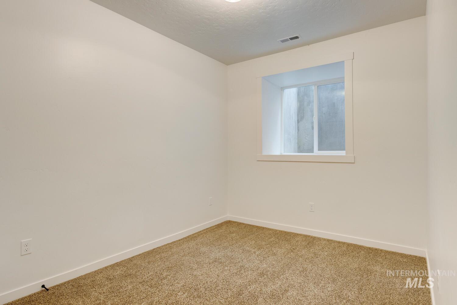 Carpeted empty room featuring baseboards and a textured ceiling