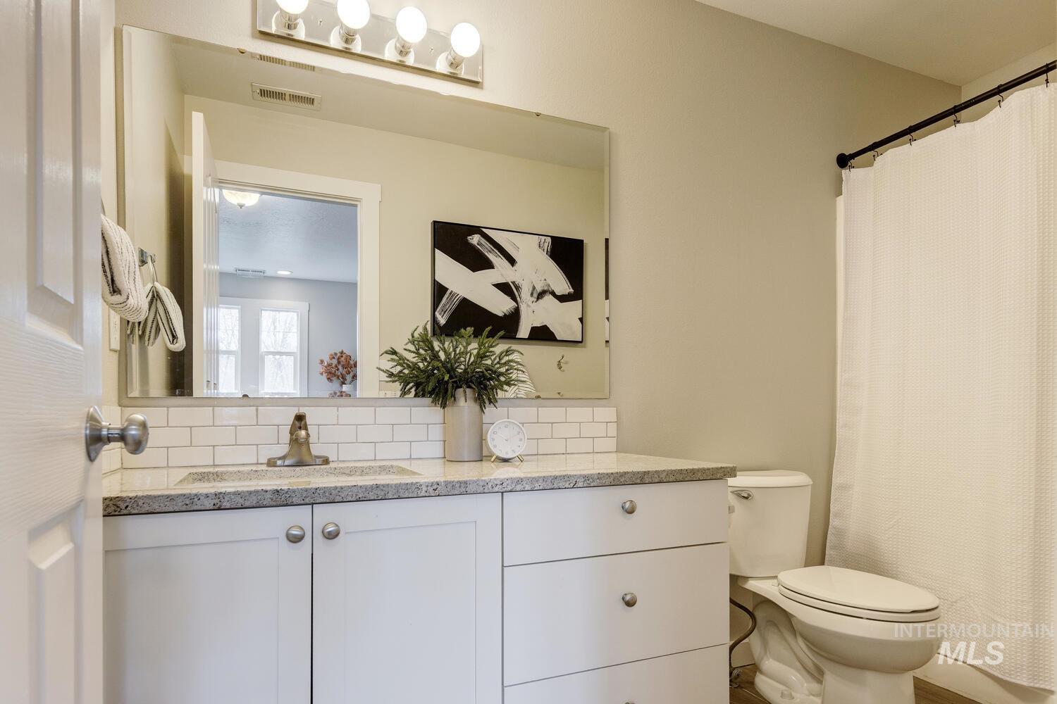 Full bath featuring vanity, a shower with curtain, and decorative backsplash
