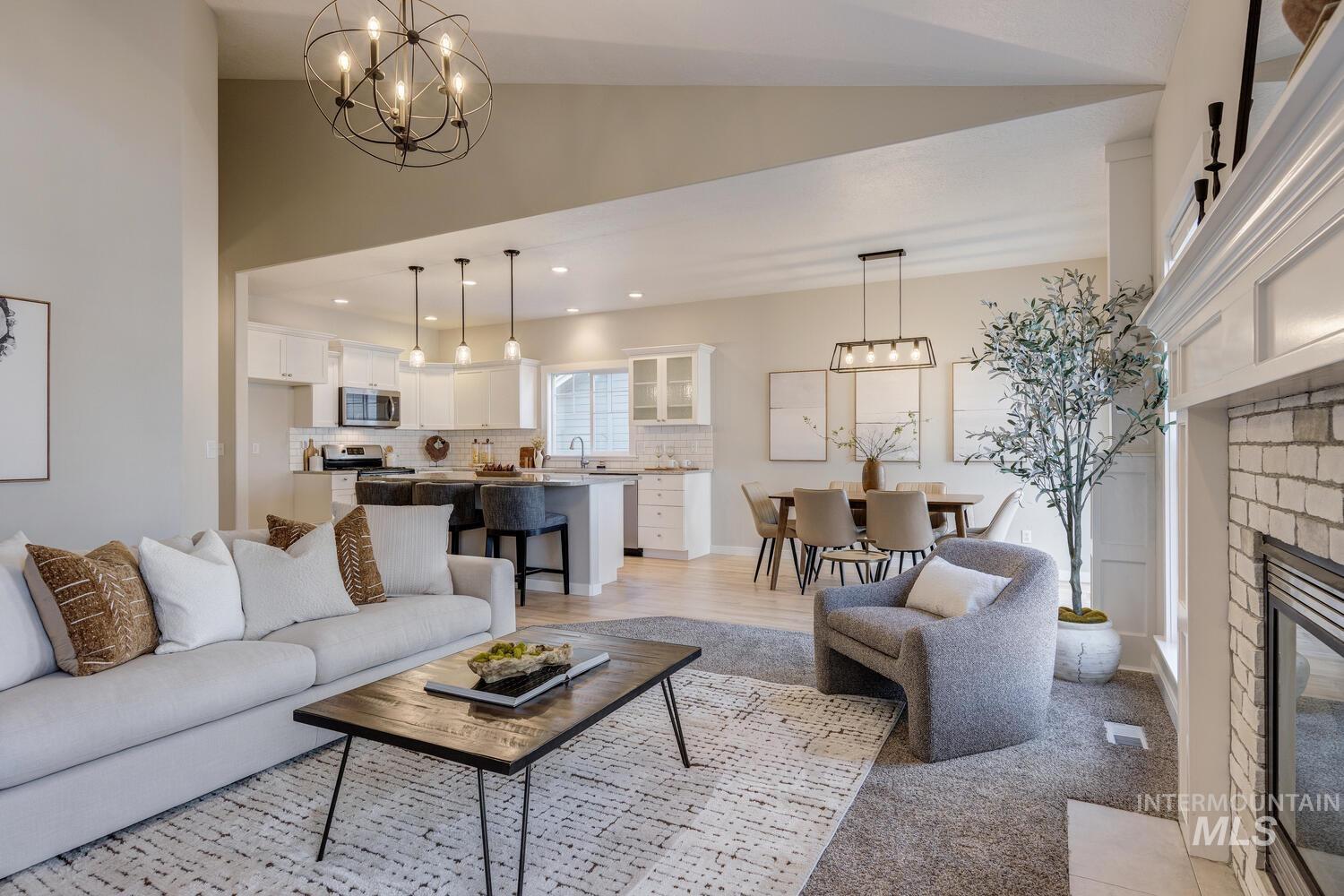 Living area featuring a chandelier, a glass covered fireplace, lofted ceiling, recessed lighting, and light wood-type flooring