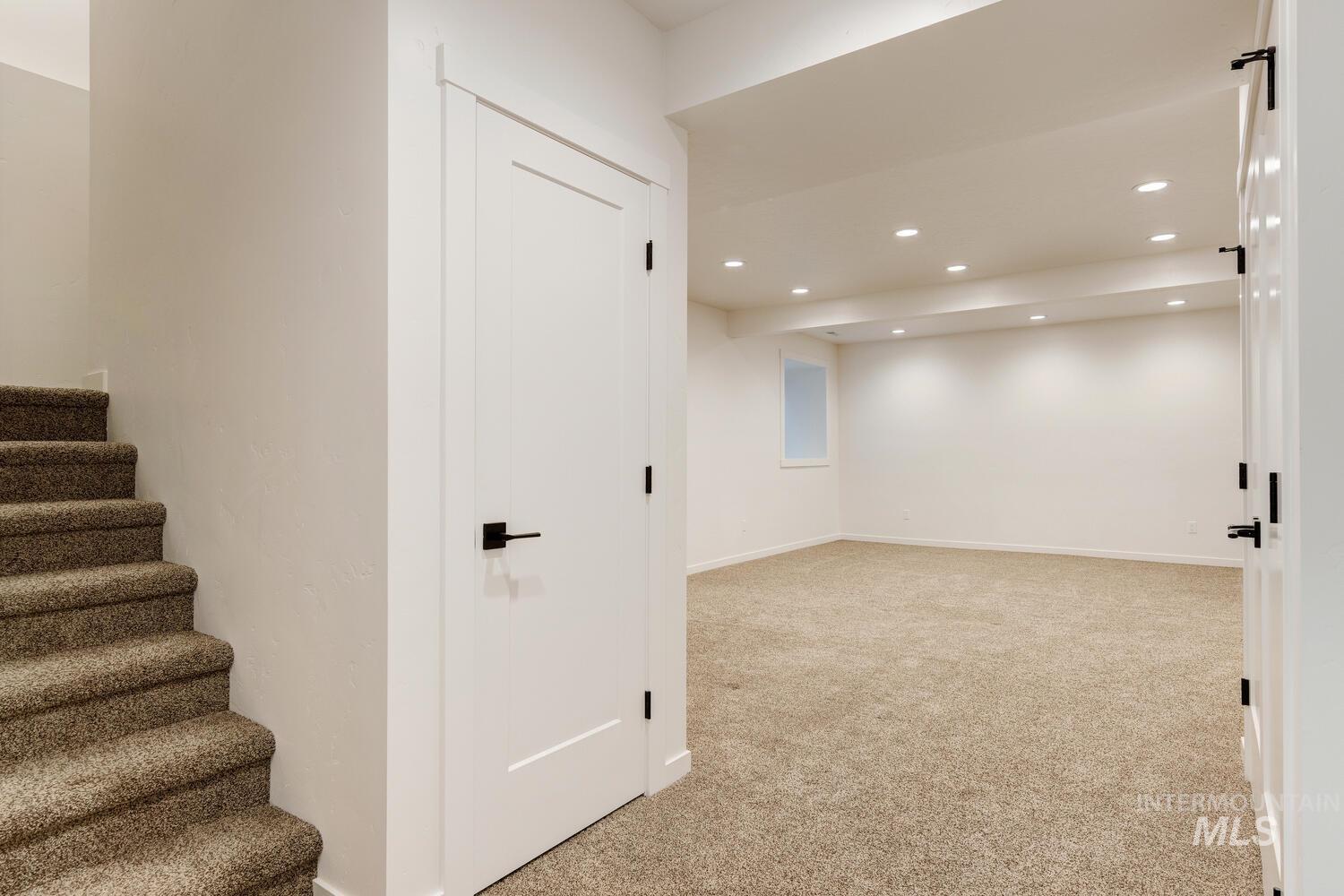 Basement featuring light colored carpet, recessed lighting, and stairway