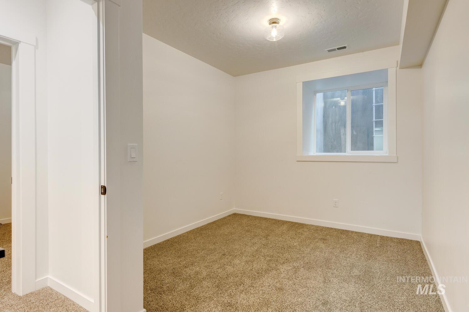 Carpeted spare room featuring baseboards and a textured ceiling