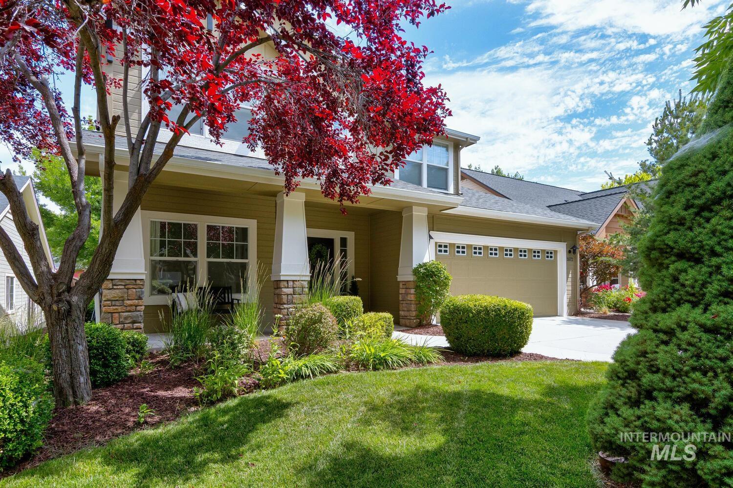 View of front of house featuring stone siding, driveway, a garage, a front lawn, and roof with shingles