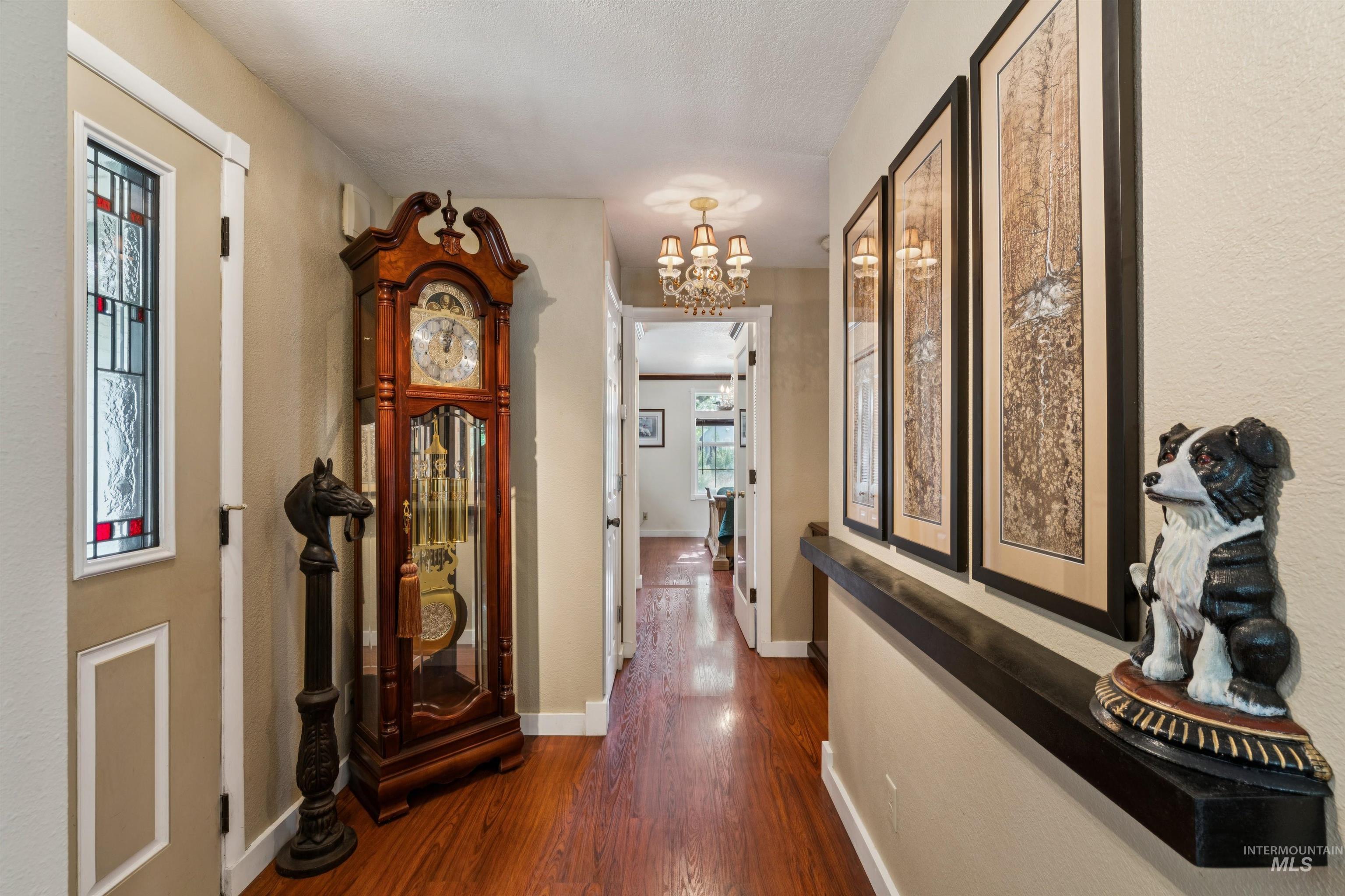 Hallway featuring wood-finish flooring, a decorative stained-glass window panel, and a built-in wall shelf