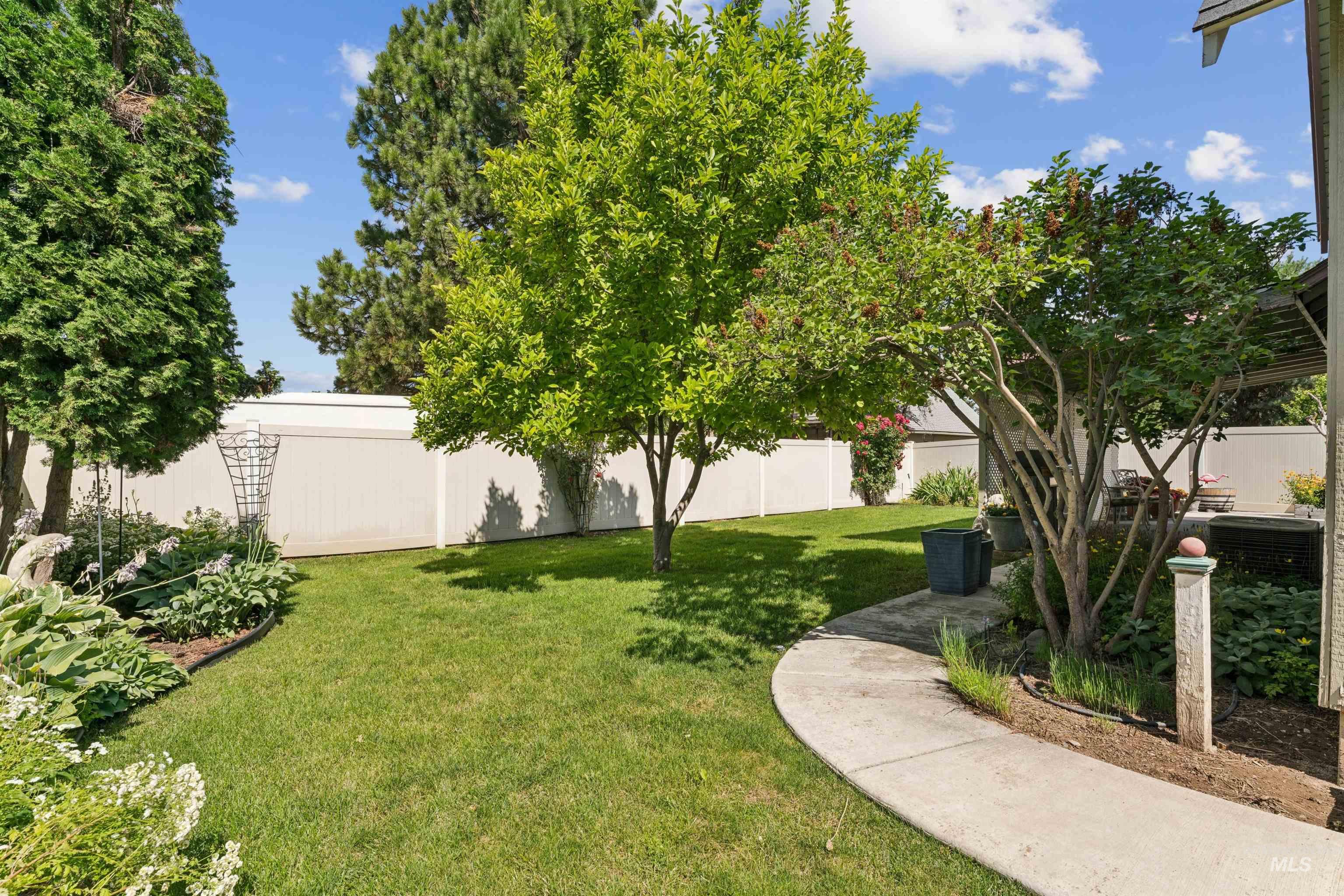 Expansive backyard featuring a lush lawn, mature trees, and established perimeter landscaping