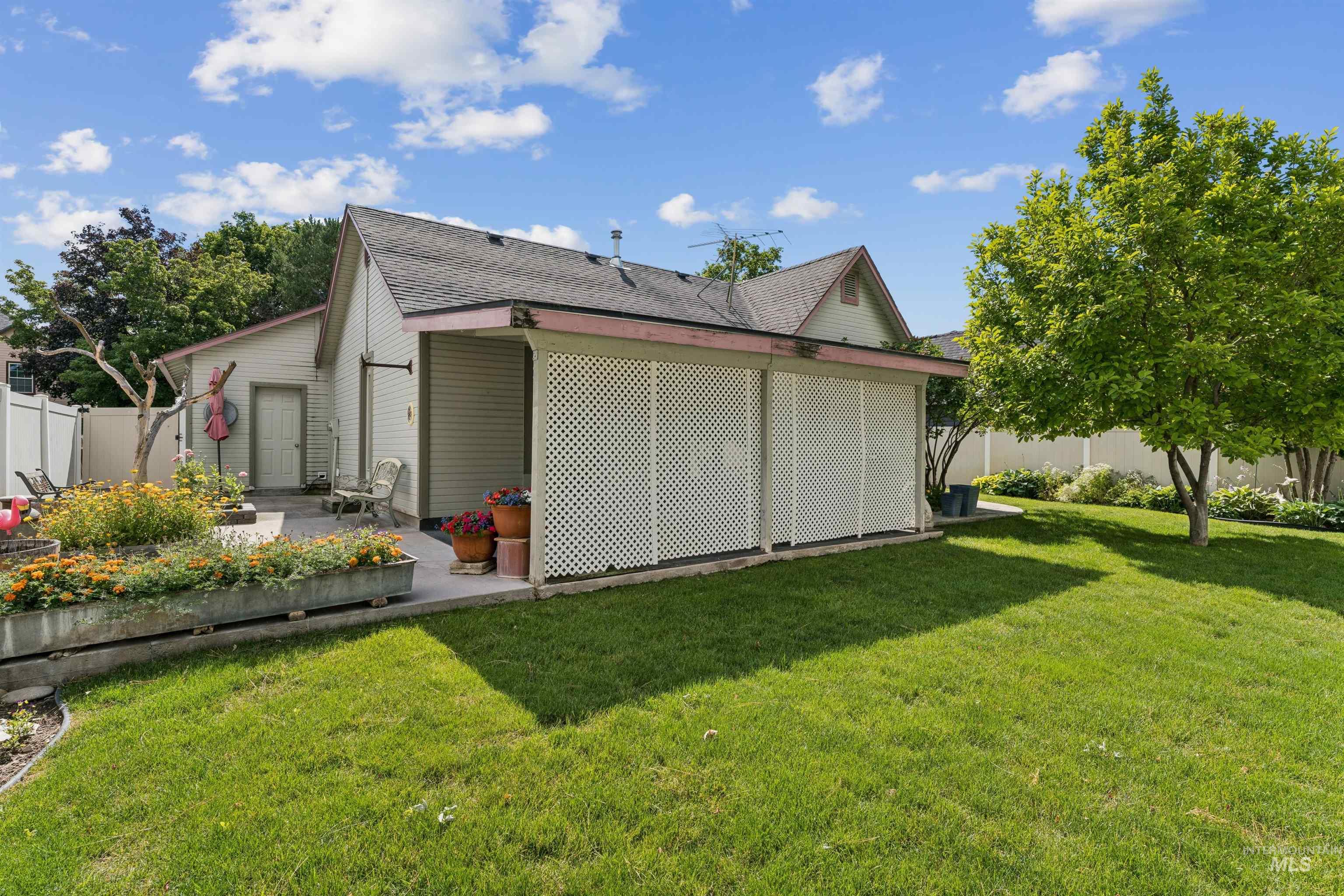 Spacious backyard featuring a manicured lawn, established shade tree, and a concrete patio
