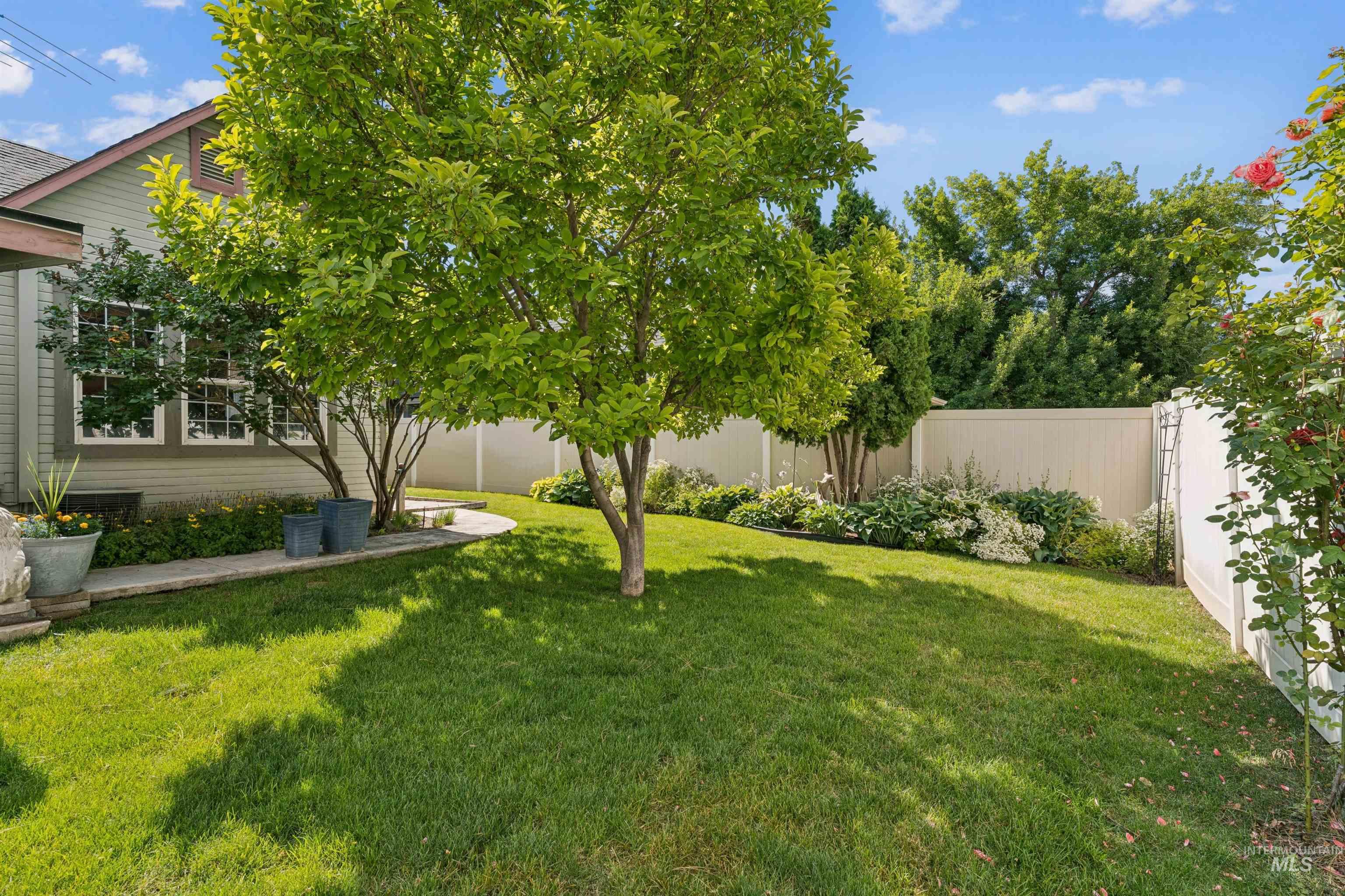 Spacious lawn area featuring mature trees and shrubbery