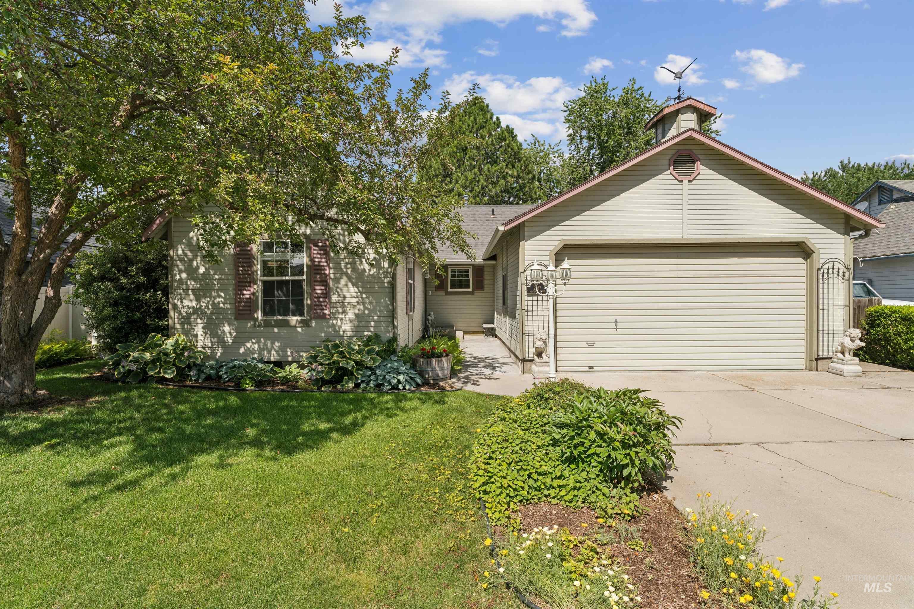 Exterior featuring an attached two-car garage, mature landscaping, and a manicured lawn