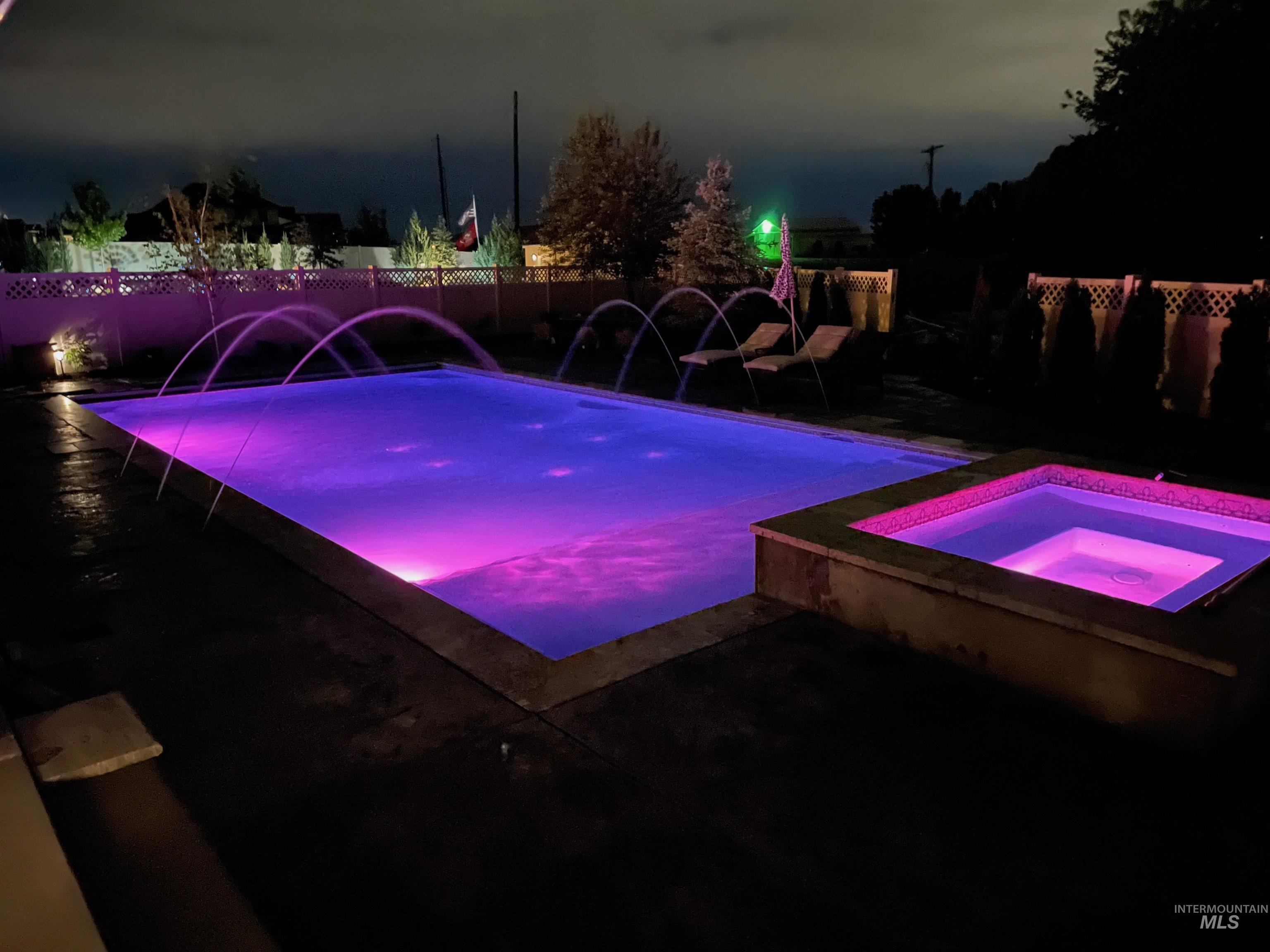 Night view of pool and spa with deck jets.