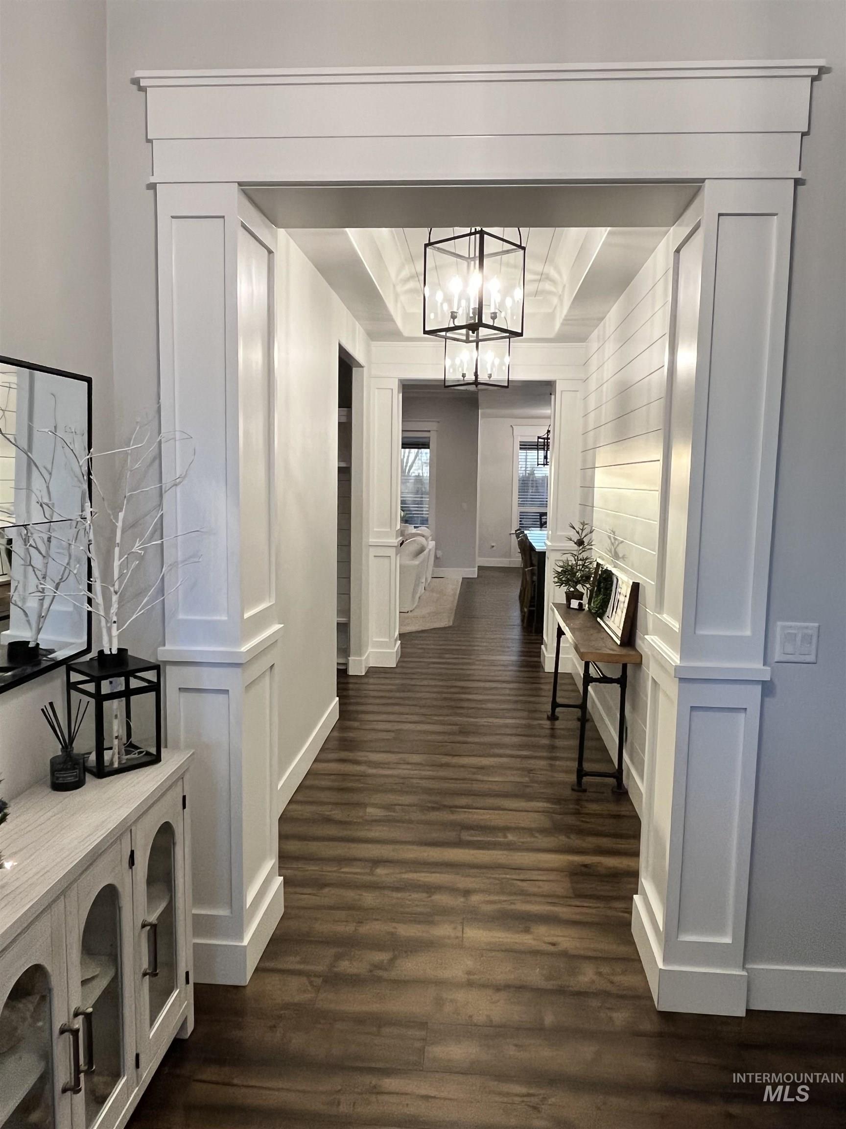 Hall with dark wood finished floors and a chandelier