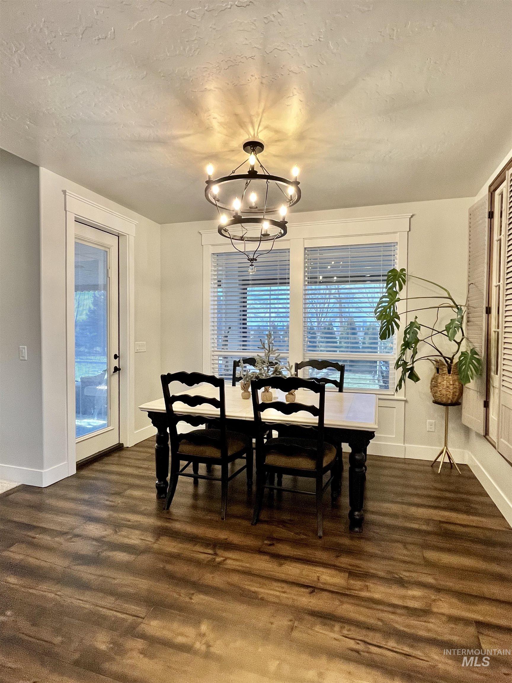 Dining room featuring dark wood finished floors, a textured ceiling, and a chandelier