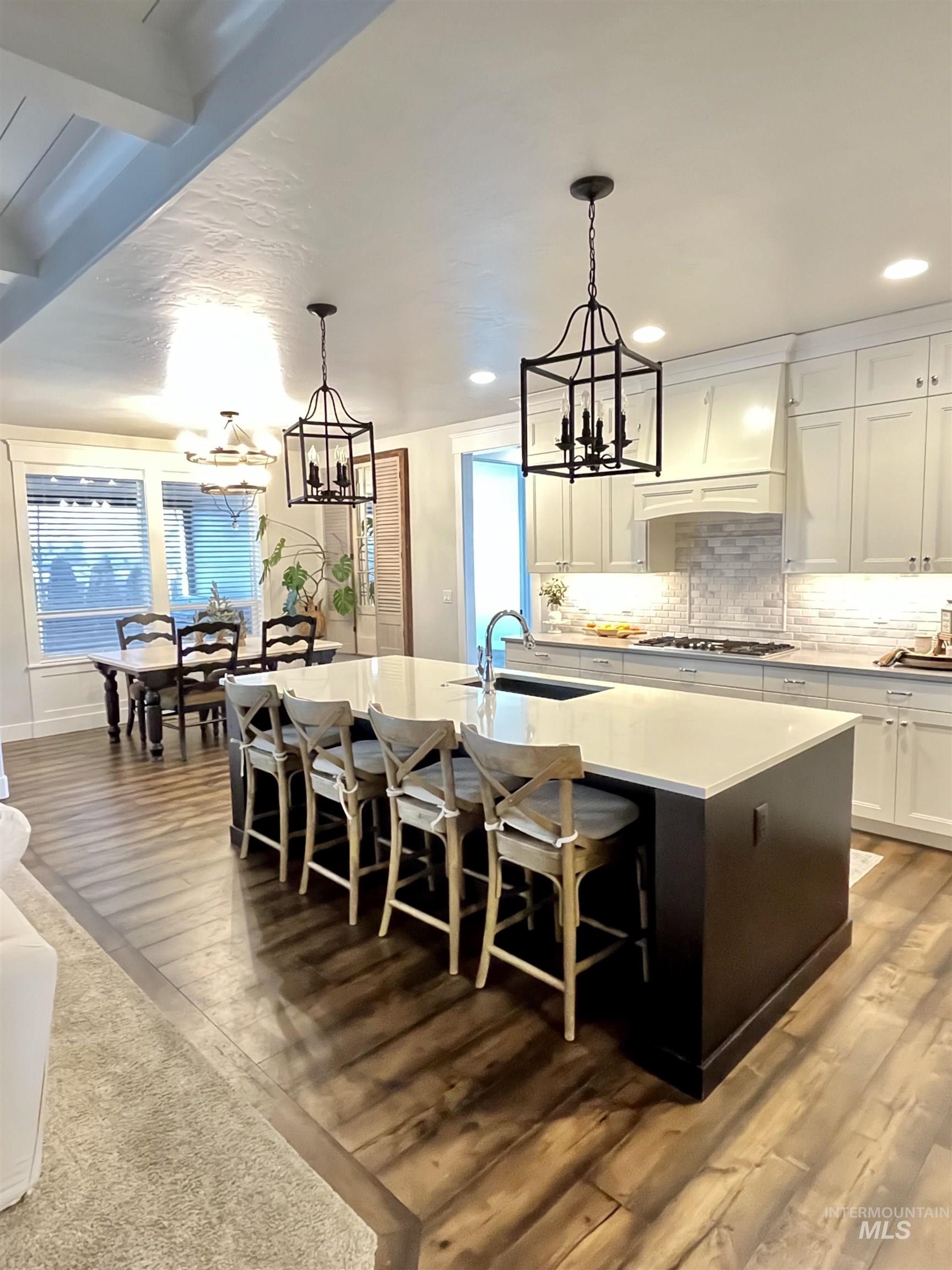 Kitchen with white cabinets, hanging light fixtures, a large island, a chandelier, and a breakfast bar