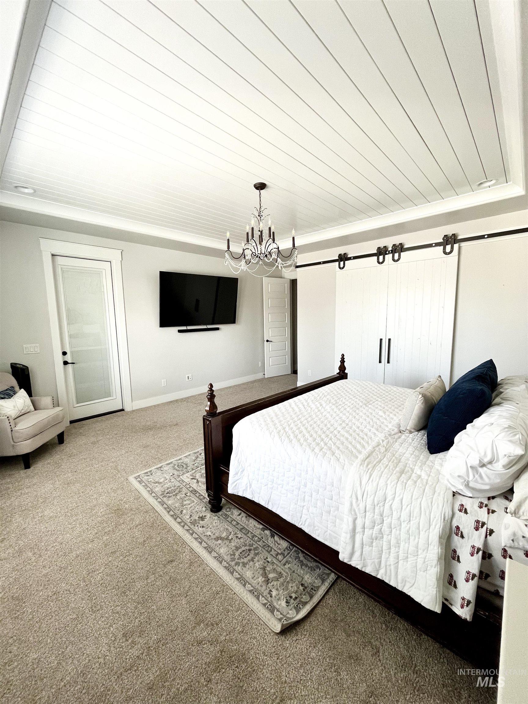 Carpeted bedroom with a chandelier and wood ceiling