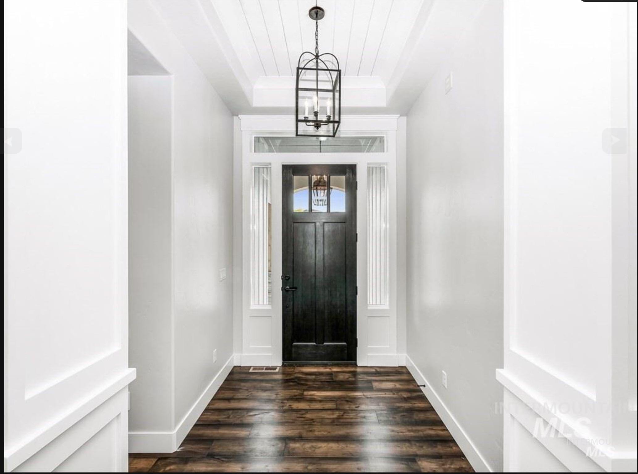 Entrance foyer with a raised ceiling, dark wood-style floors, and a chandelier