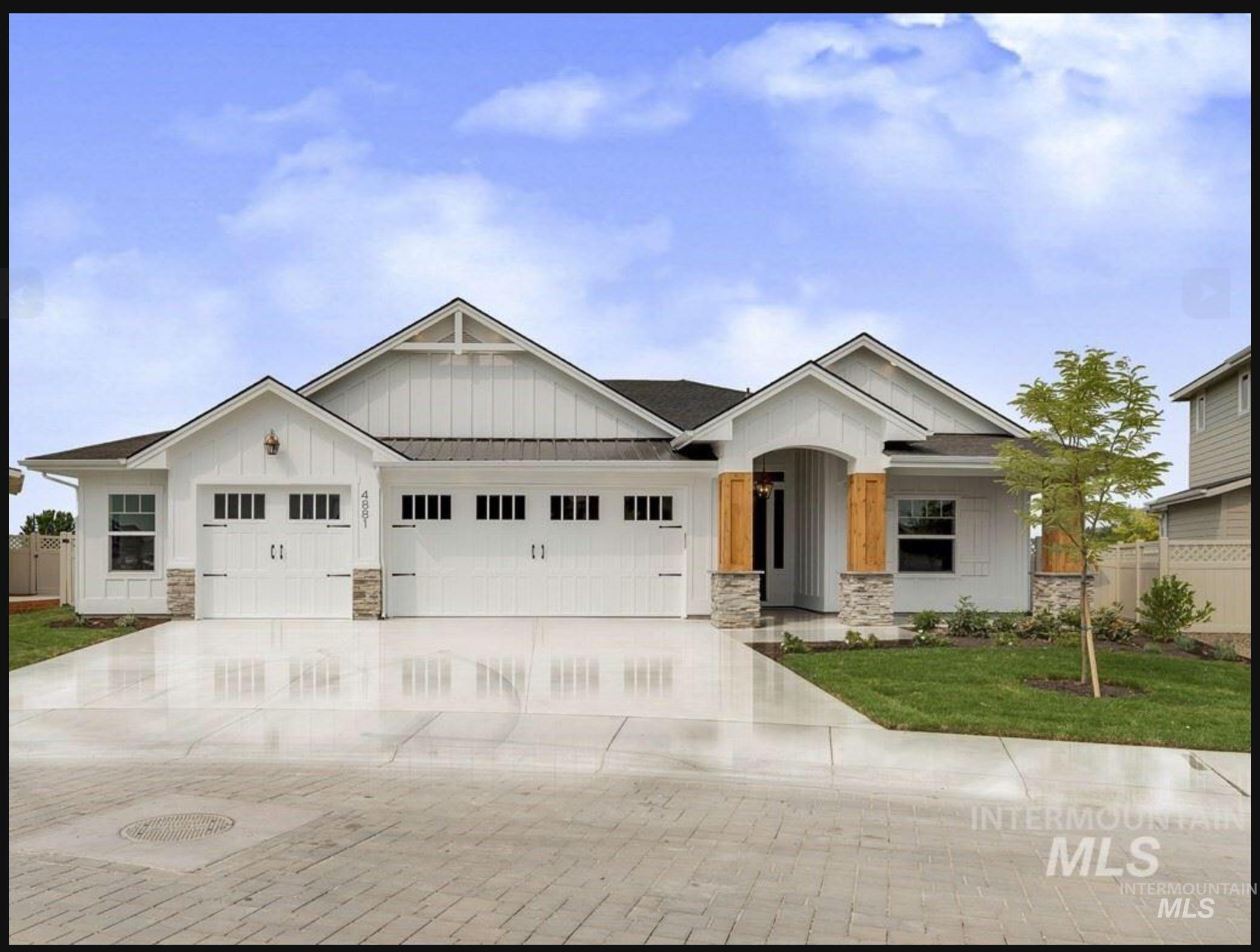 View of front of property with board and batten siding, stone siding, an attached garage, and driveway