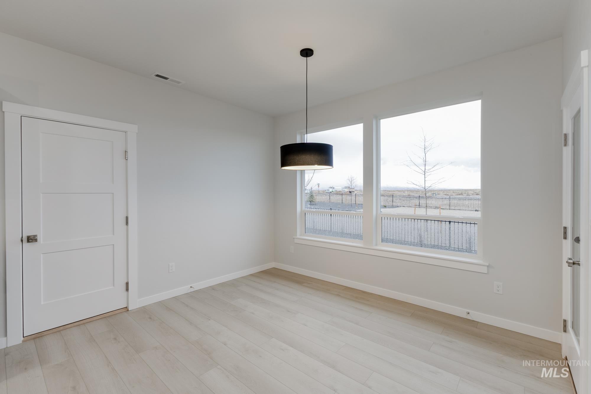 Unfurnished dining area with baseboards and light wood-style flooring