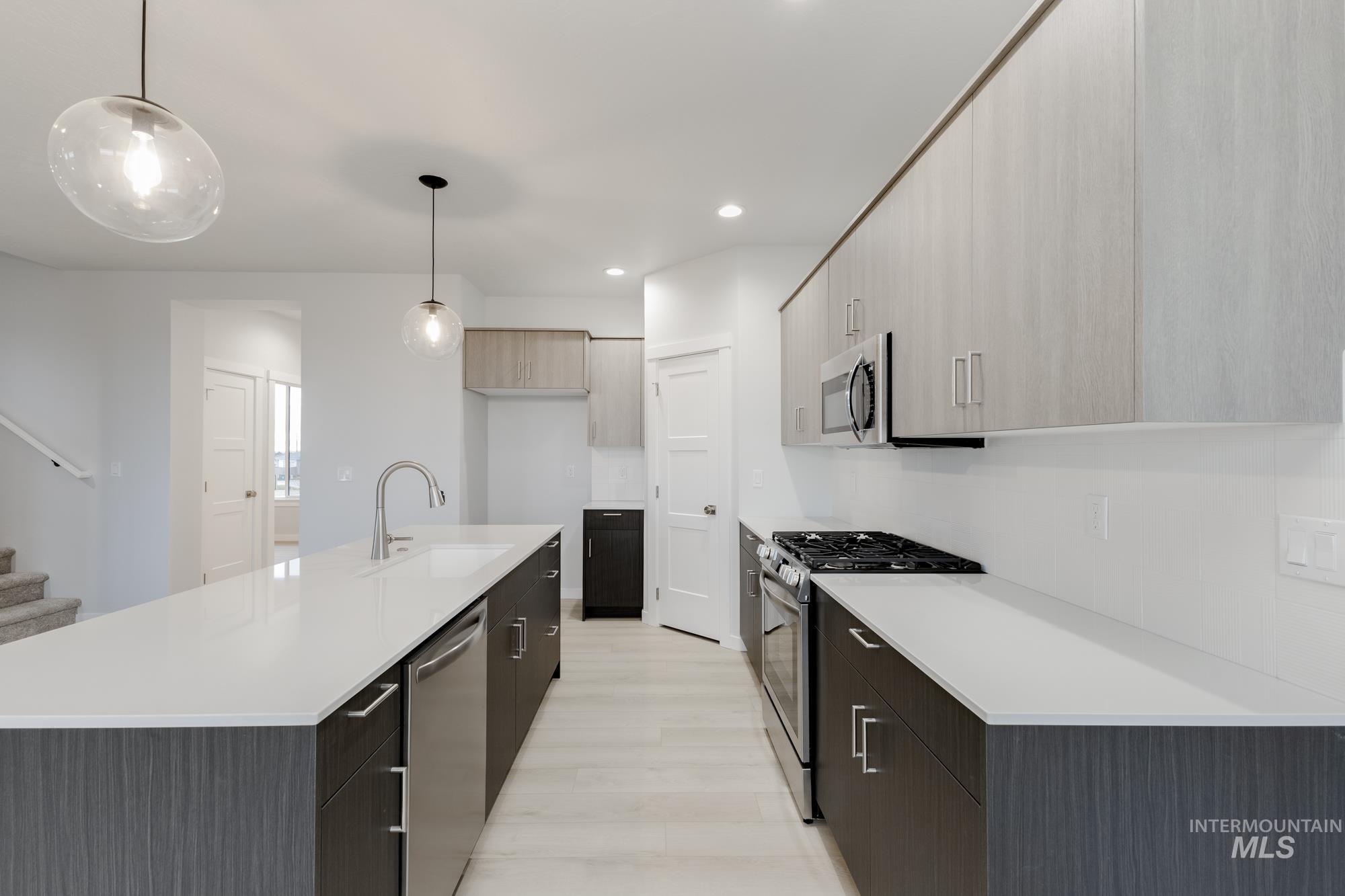 Kitchen with modern cabinets, stainless steel appliances, a kitchen island with sink, pendant lighting, and recessed lighting