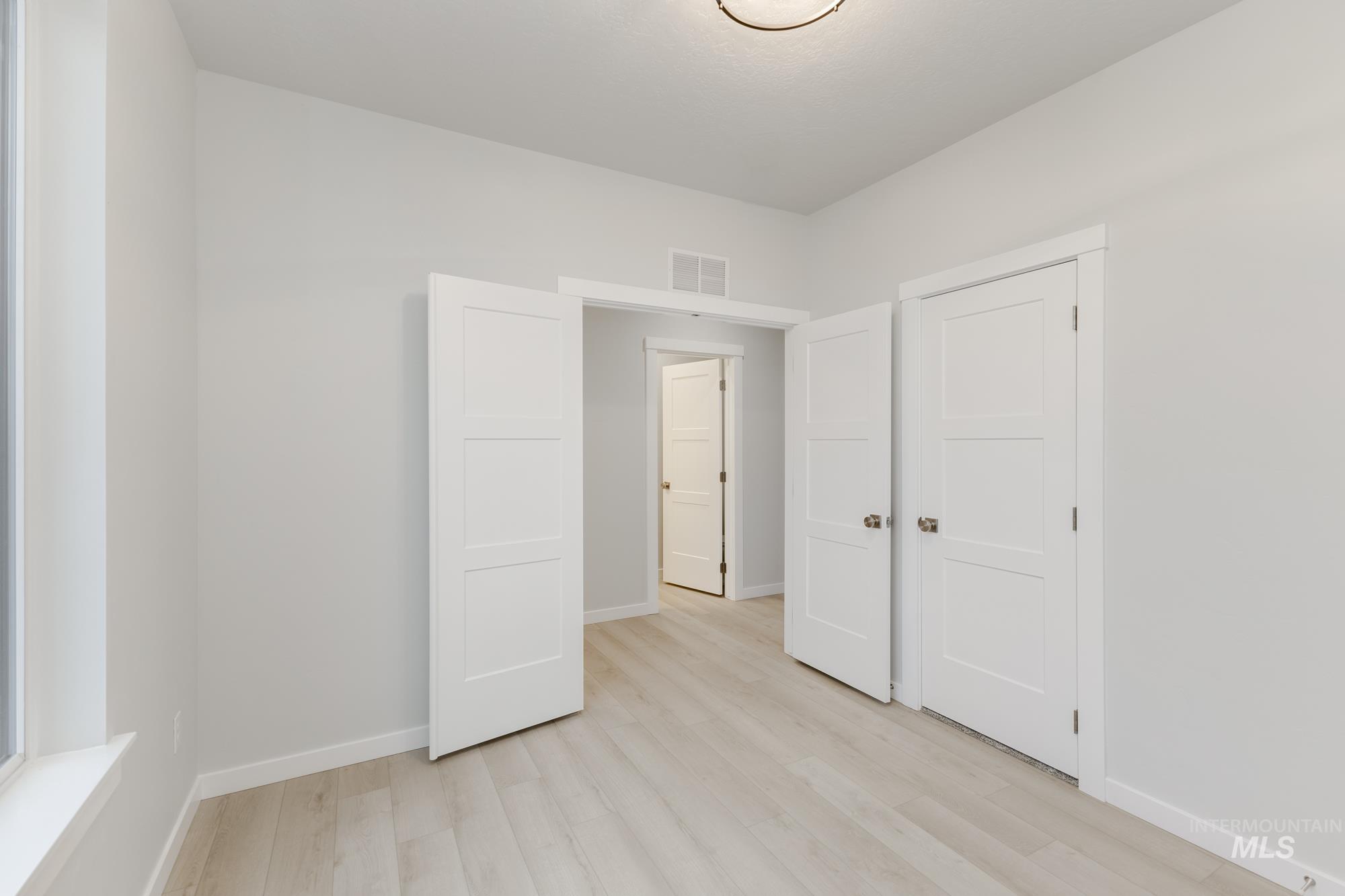 Unfurnished bedroom with light wood finished floors and baseboards