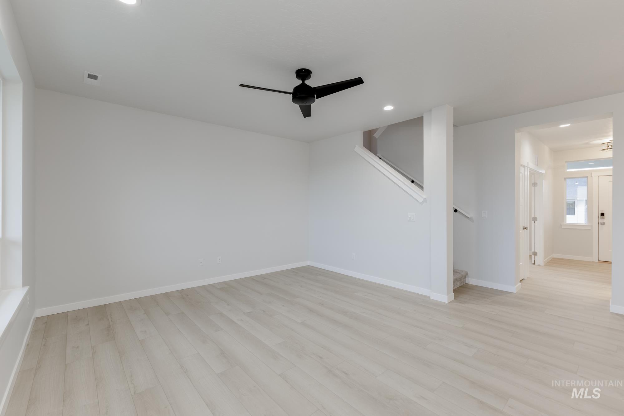 Unfurnished room featuring ceiling fan, light wood finished floors, recessed lighting, and stairway