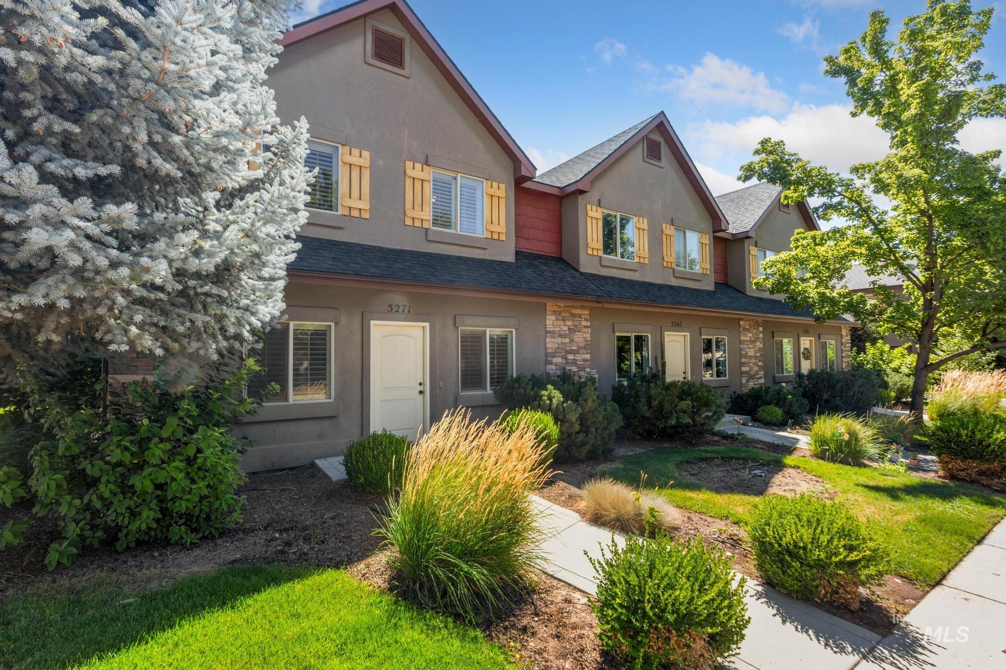 View of front of home featuring roof with shingles, stone siding, a front yard, and stucco siding