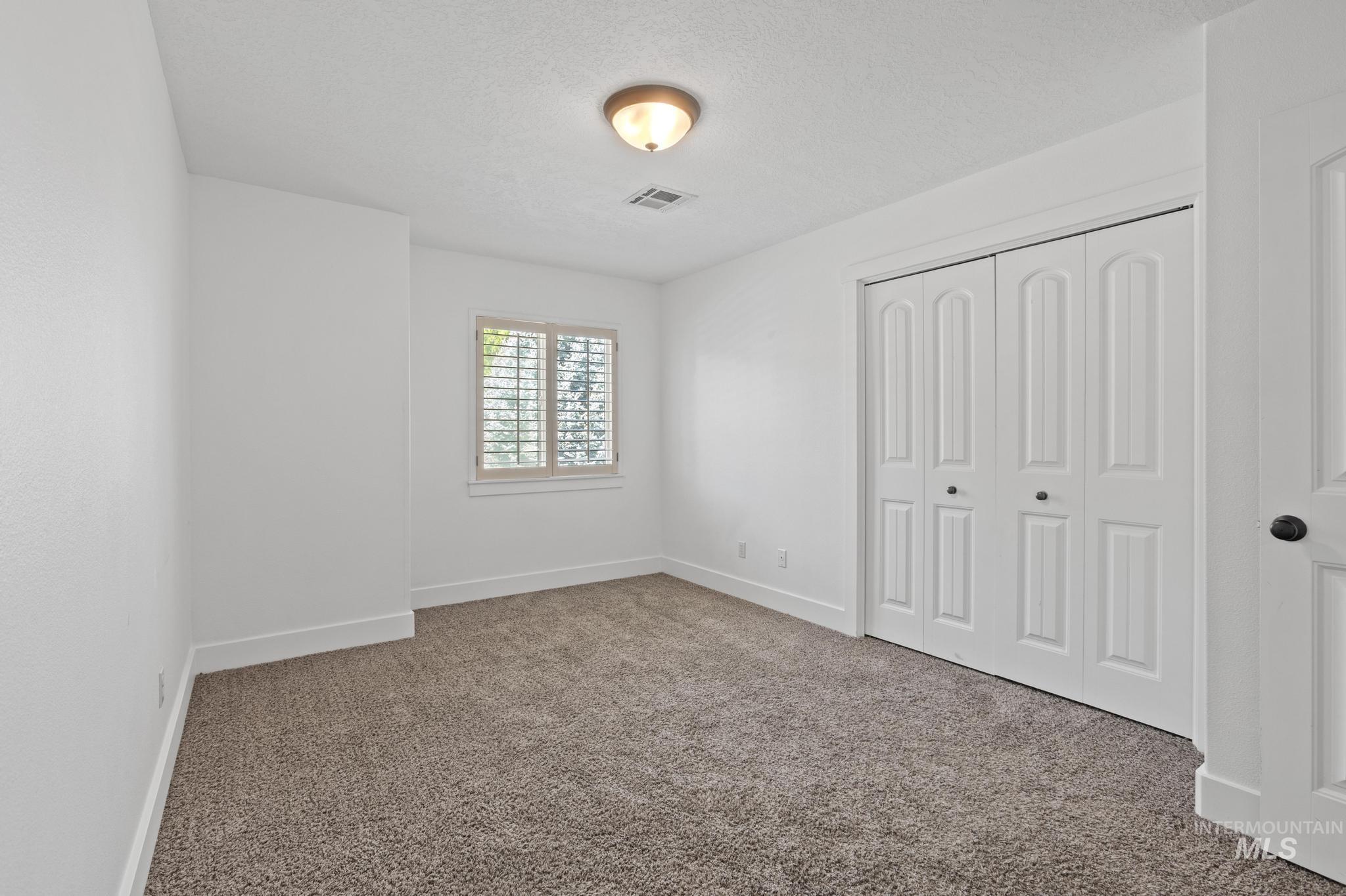 Unfurnished bedroom featuring carpet flooring, a textured ceiling, and a closet