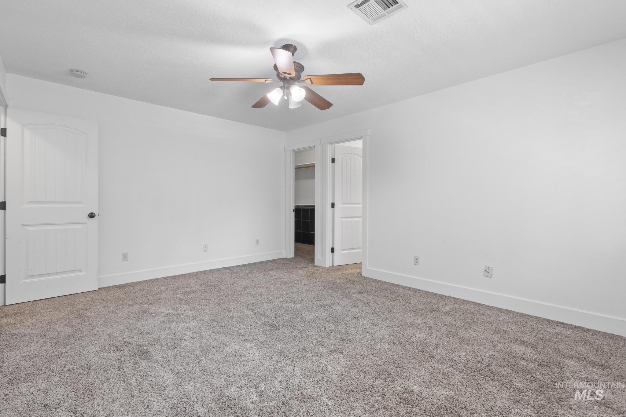 Unfurnished bedroom with a walk in closet, light carpet, and ceiling fan