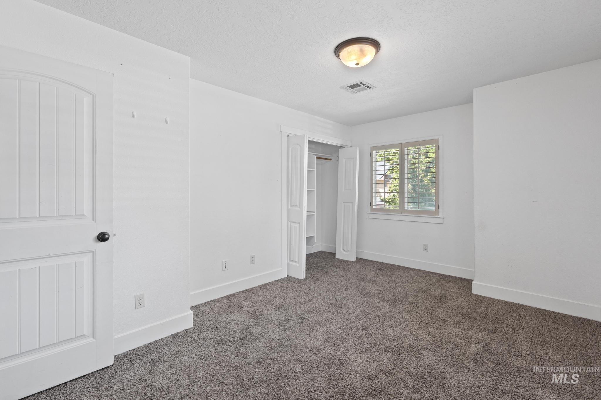 Unfurnished bedroom featuring dark carpet, a closet, and a textured ceiling