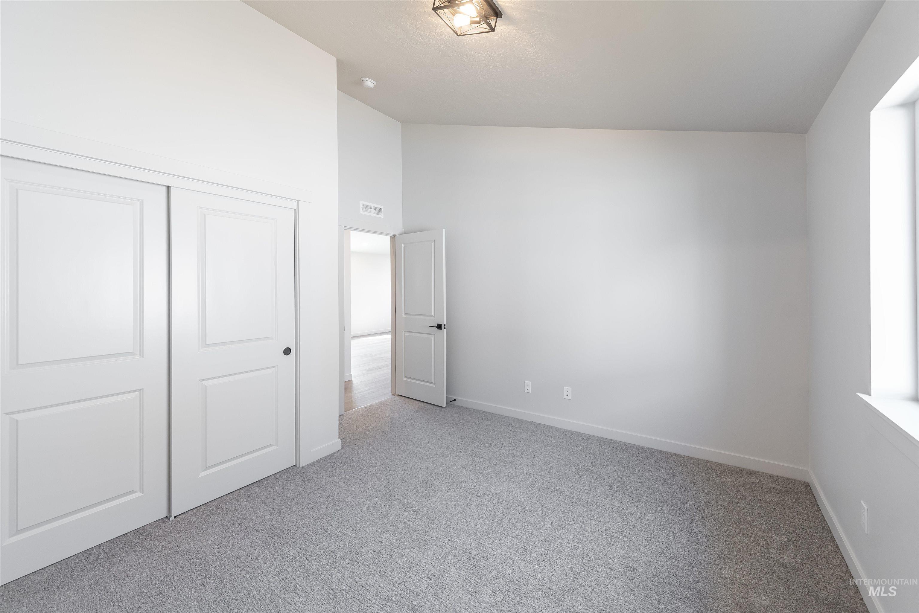 Unfurnished bedroom featuring light carpet, a closet, and high vaulted ceiling