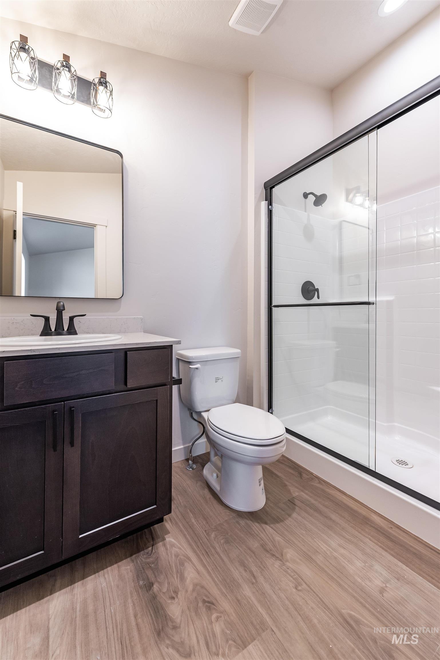Bathroom with light wood-style flooring, vanity, and a shower stall