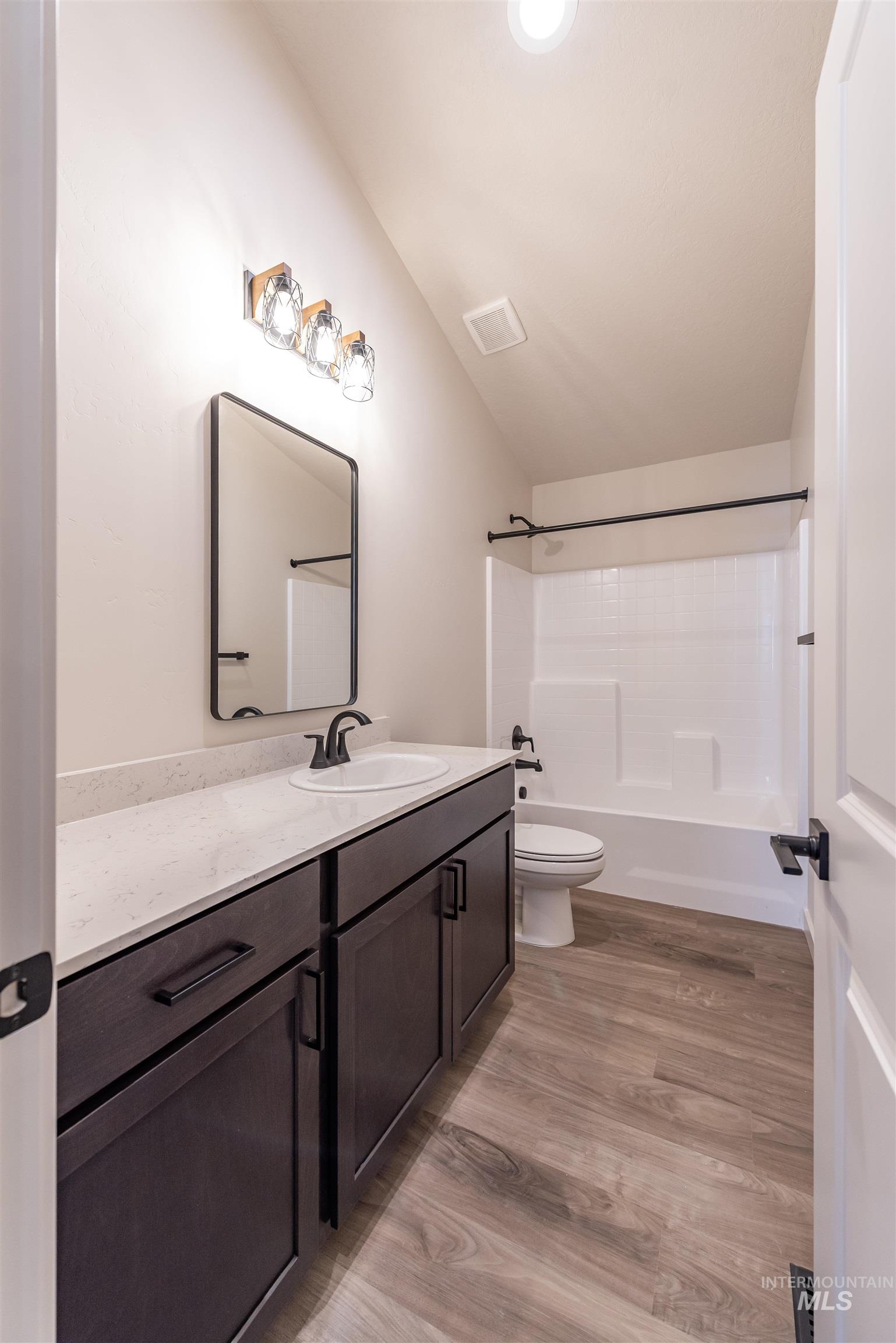 Full bath featuring washtub / shower combination, vanity, and light wood-type flooring