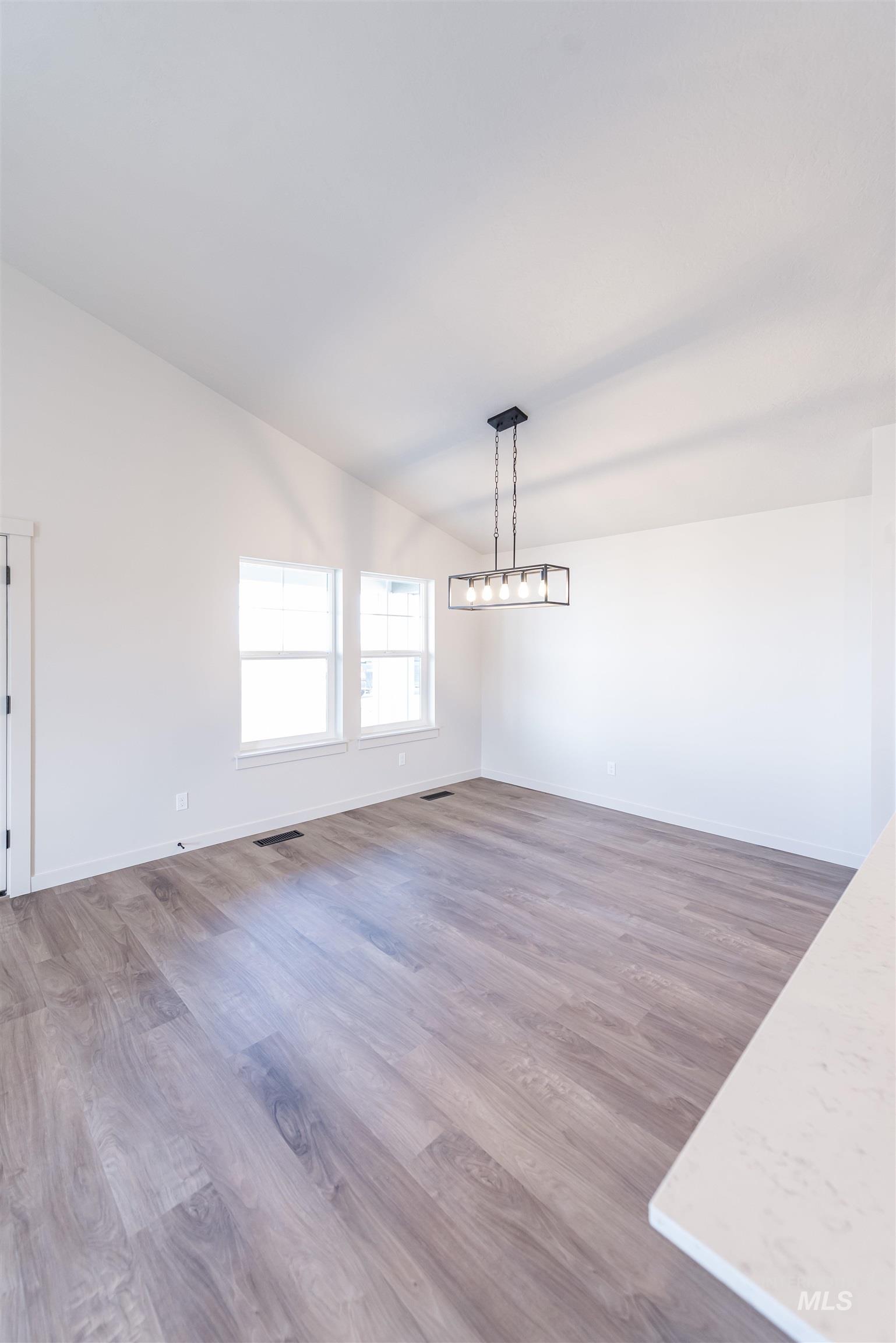 Unfurnished dining area featuring wood finished floors and vaulted ceiling