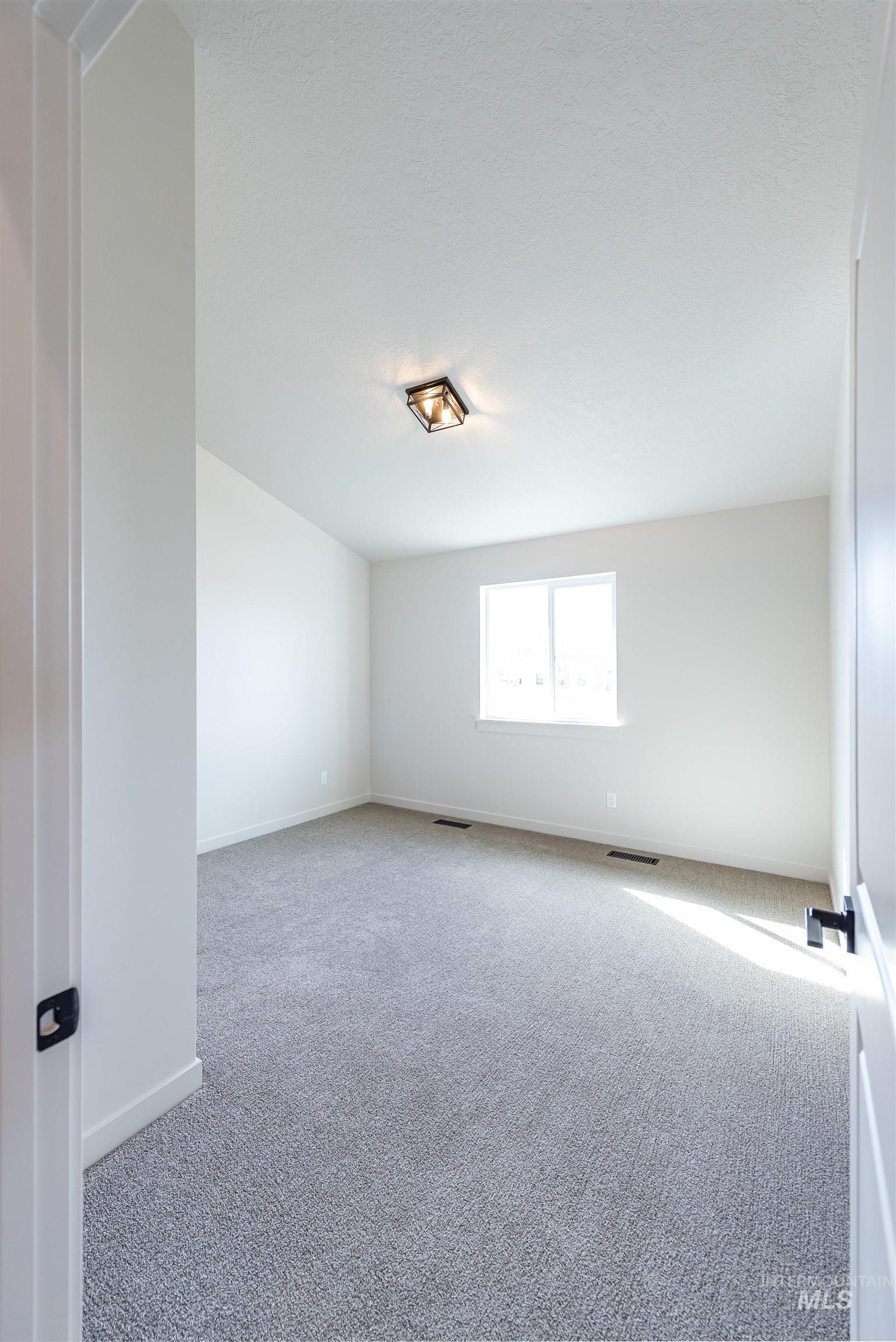Carpeted empty room with baseboards and a textured ceiling