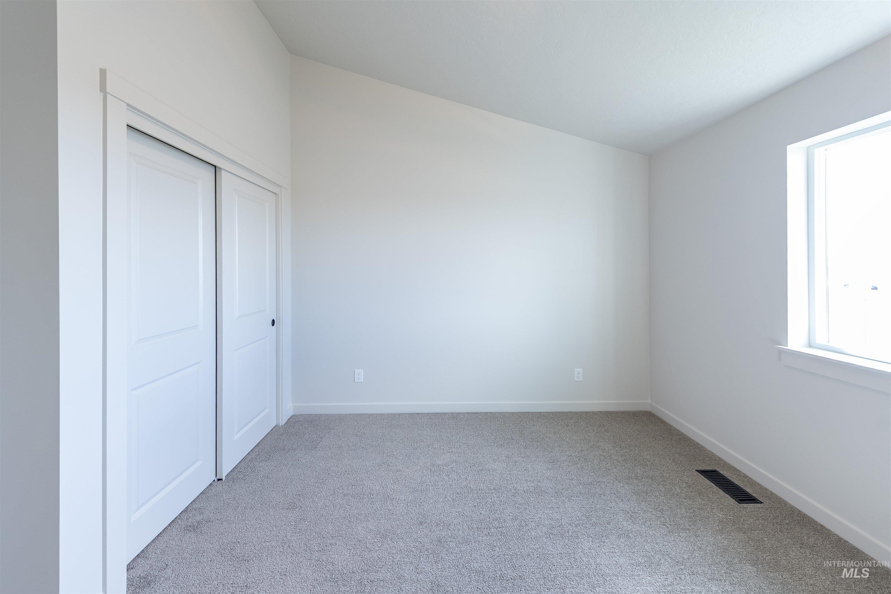 Unfurnished bedroom featuring light carpet and a closet