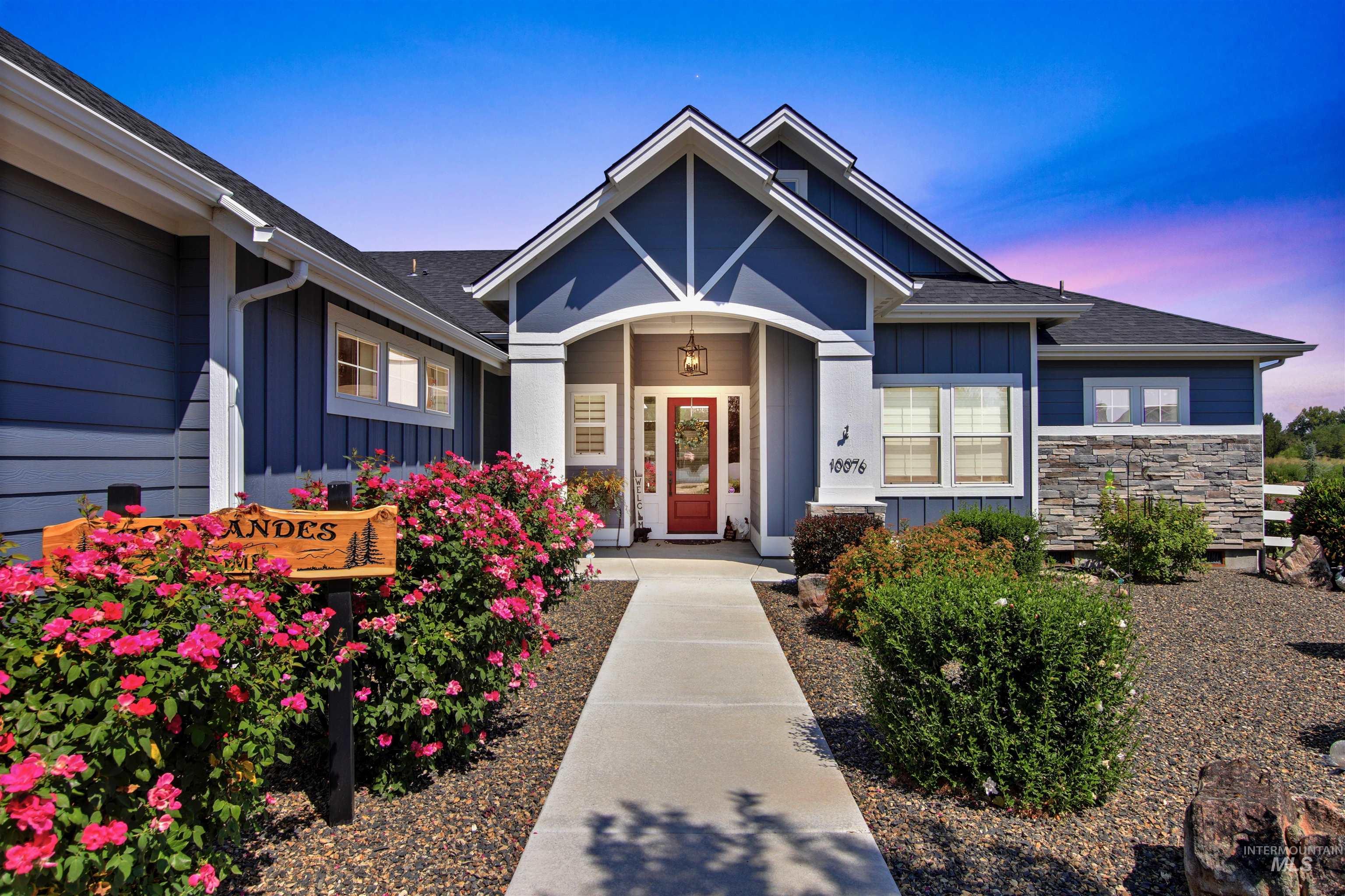 Exterior entry at dusk with board and batten siding, a shingled roof, and stone siding