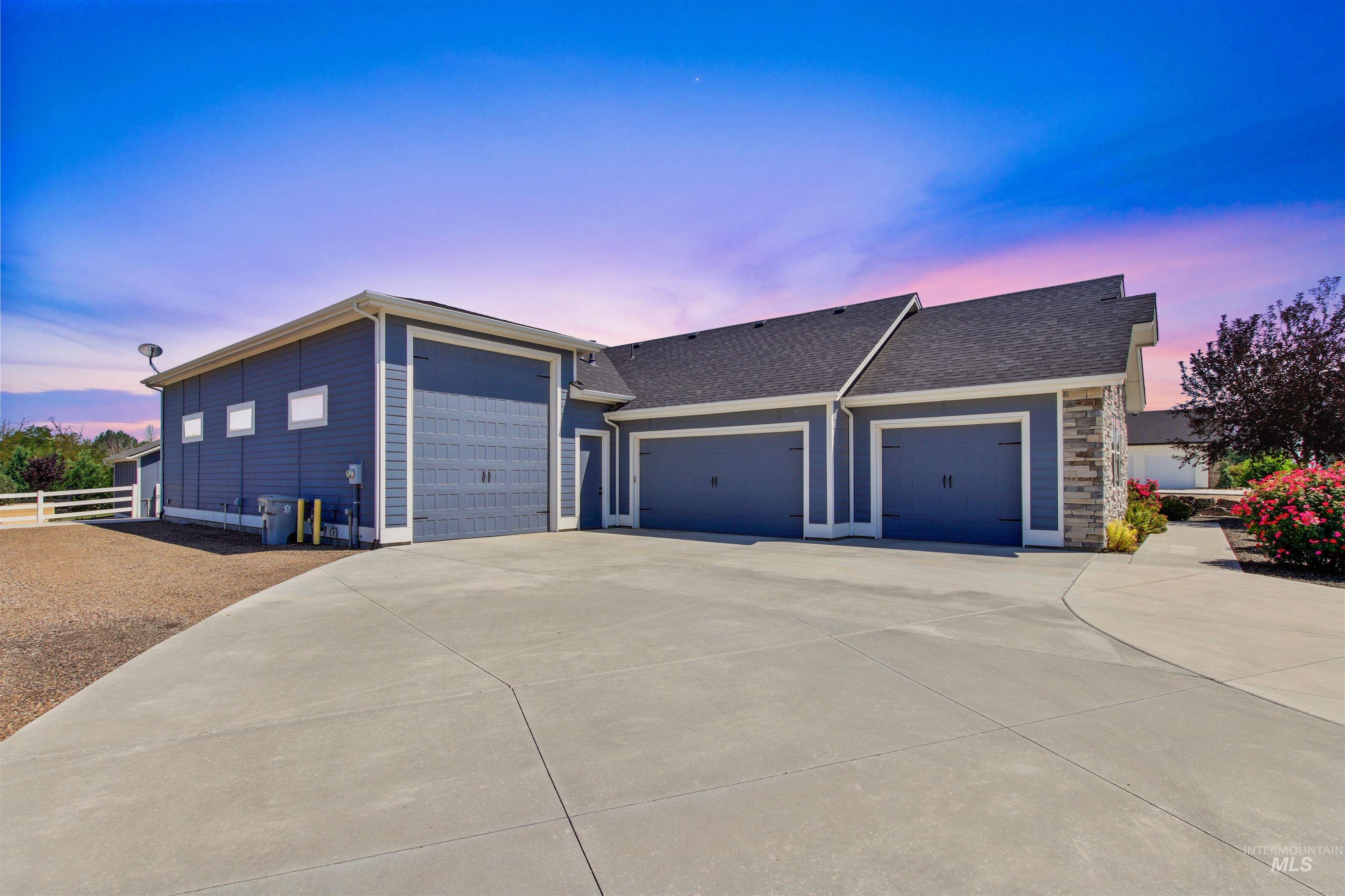 View of front of house with driveway, a shingled roof, a garage, and stone siding